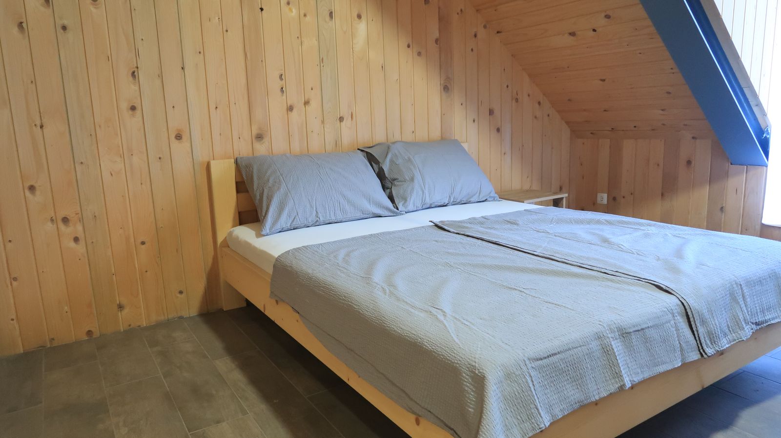 Timber bedroom with a large double bed in the three-bedroom apartment
